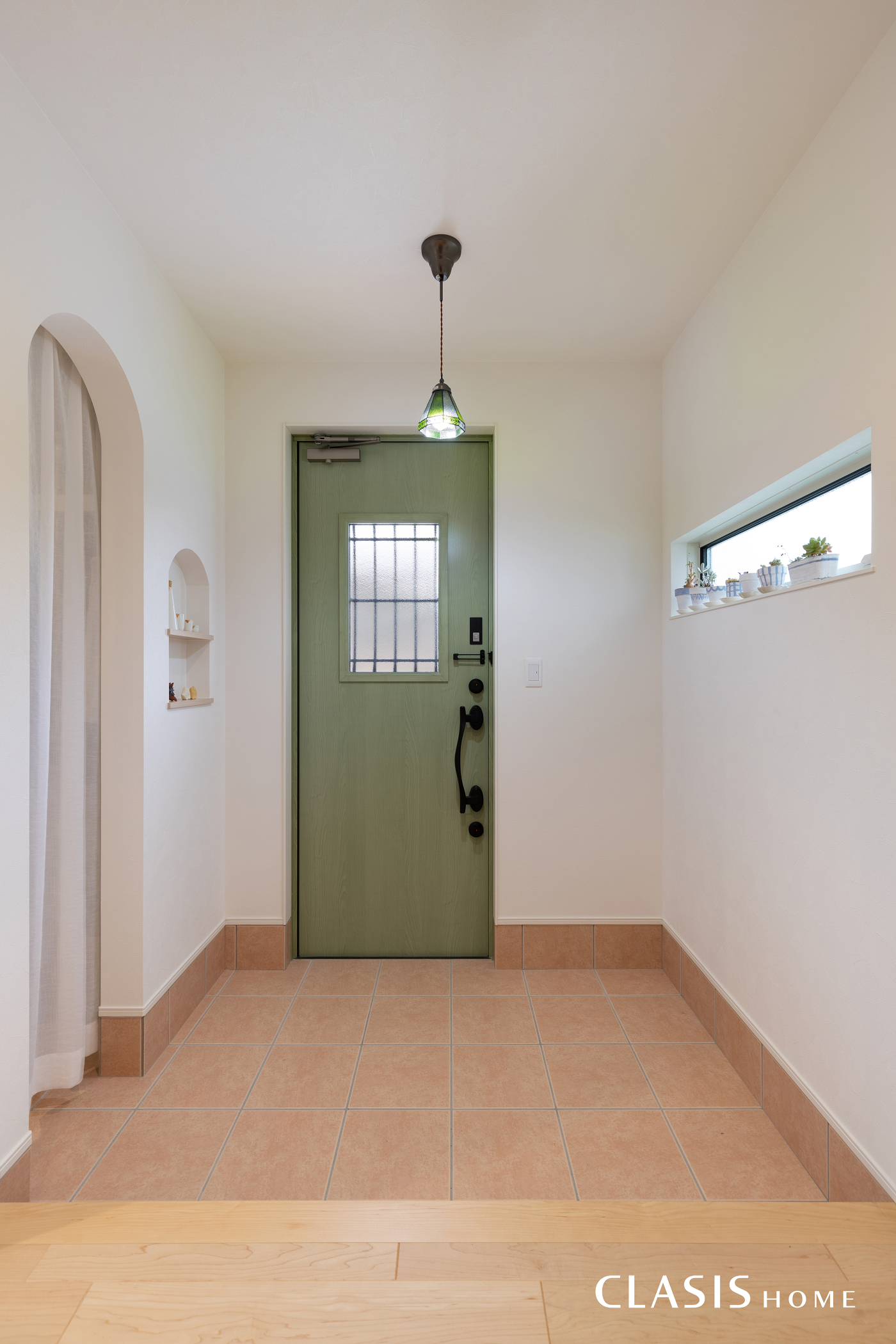 白の塗り壁やパステルグリーンの玄関扉にも合うテラコッタ色の玄関タイル。