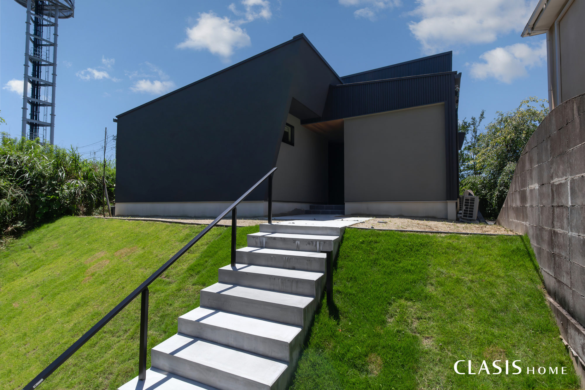 ブラックのガルバリウム鋼板をベースにブラック・グレーの塗り壁を組み合わせた、斜め壁が際立つ外観。