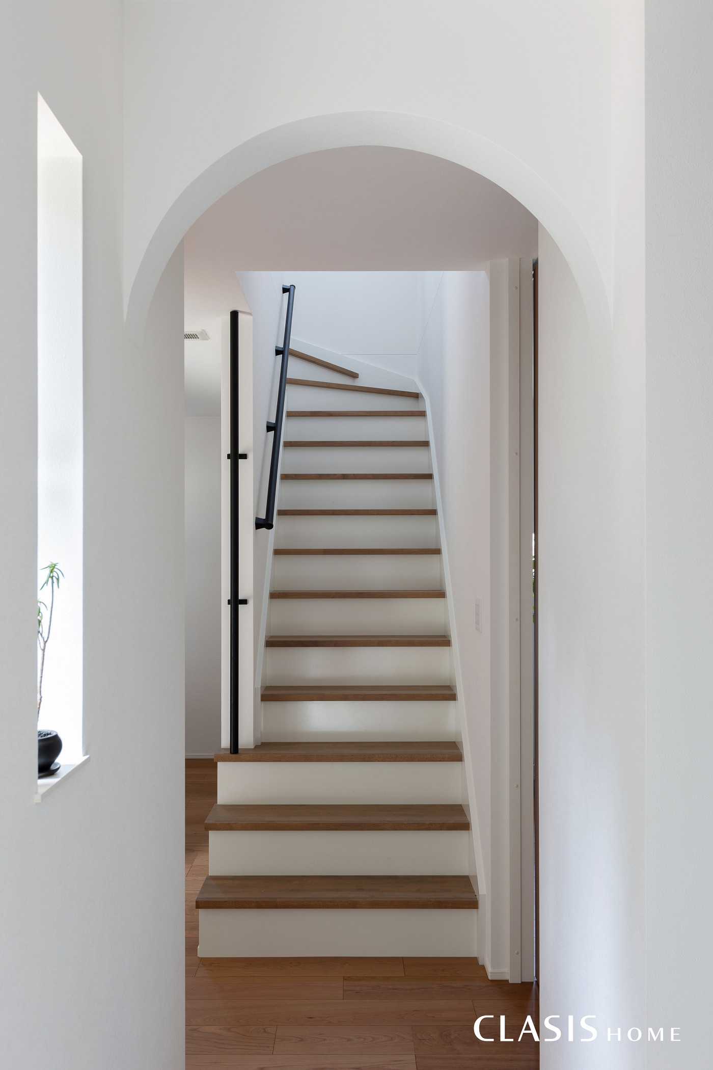アールの垂れ壁が柔らかく空間を区切り、白の蹴込み板が爽やかな階段。