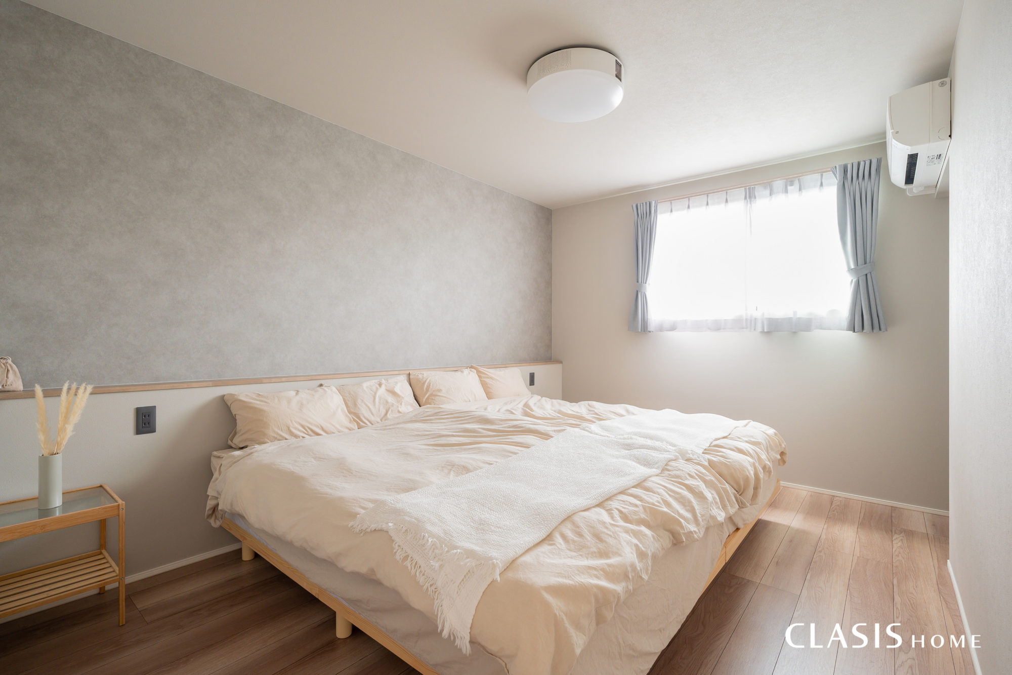 ライトグレーに木目、淡い色使いを基調とした寝室。