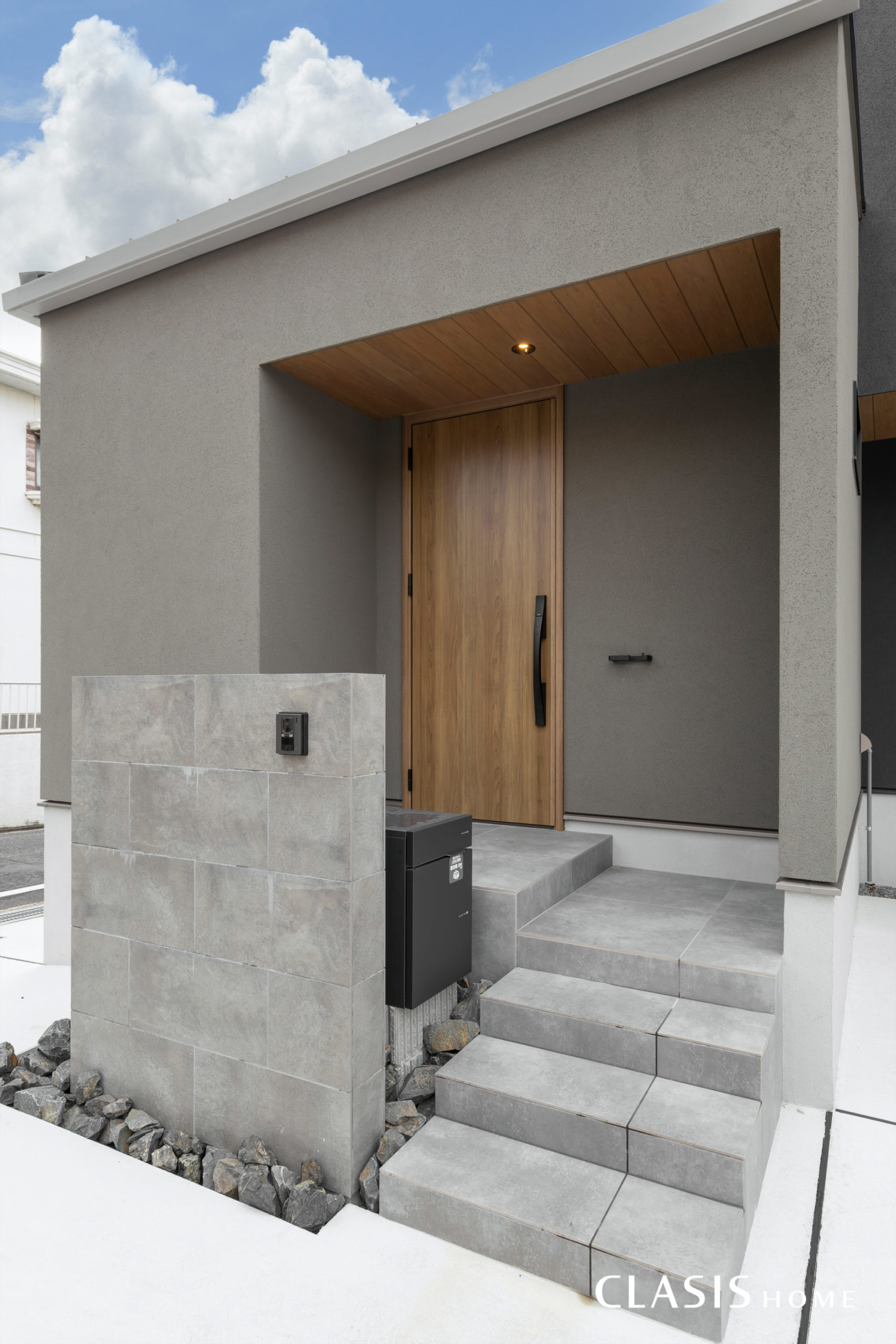 グレージュの塗り壁と木目の玄関扉を採用し、より柔らかい印象の玄関。