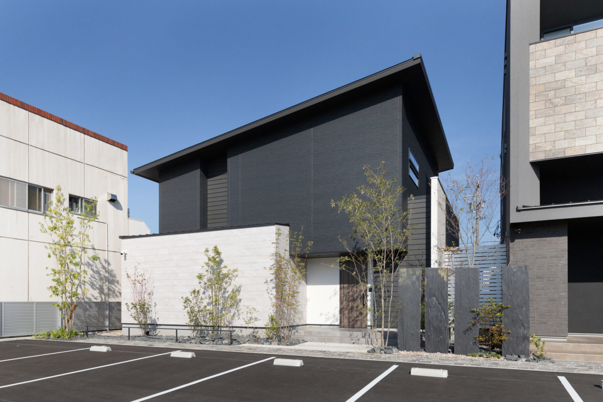 モノトーンでまとめたスタイリッシュな外観。窓を配置せずタイルやサイディング、アクセントのラップサイディングという素材を前面に押し出したデザイン。