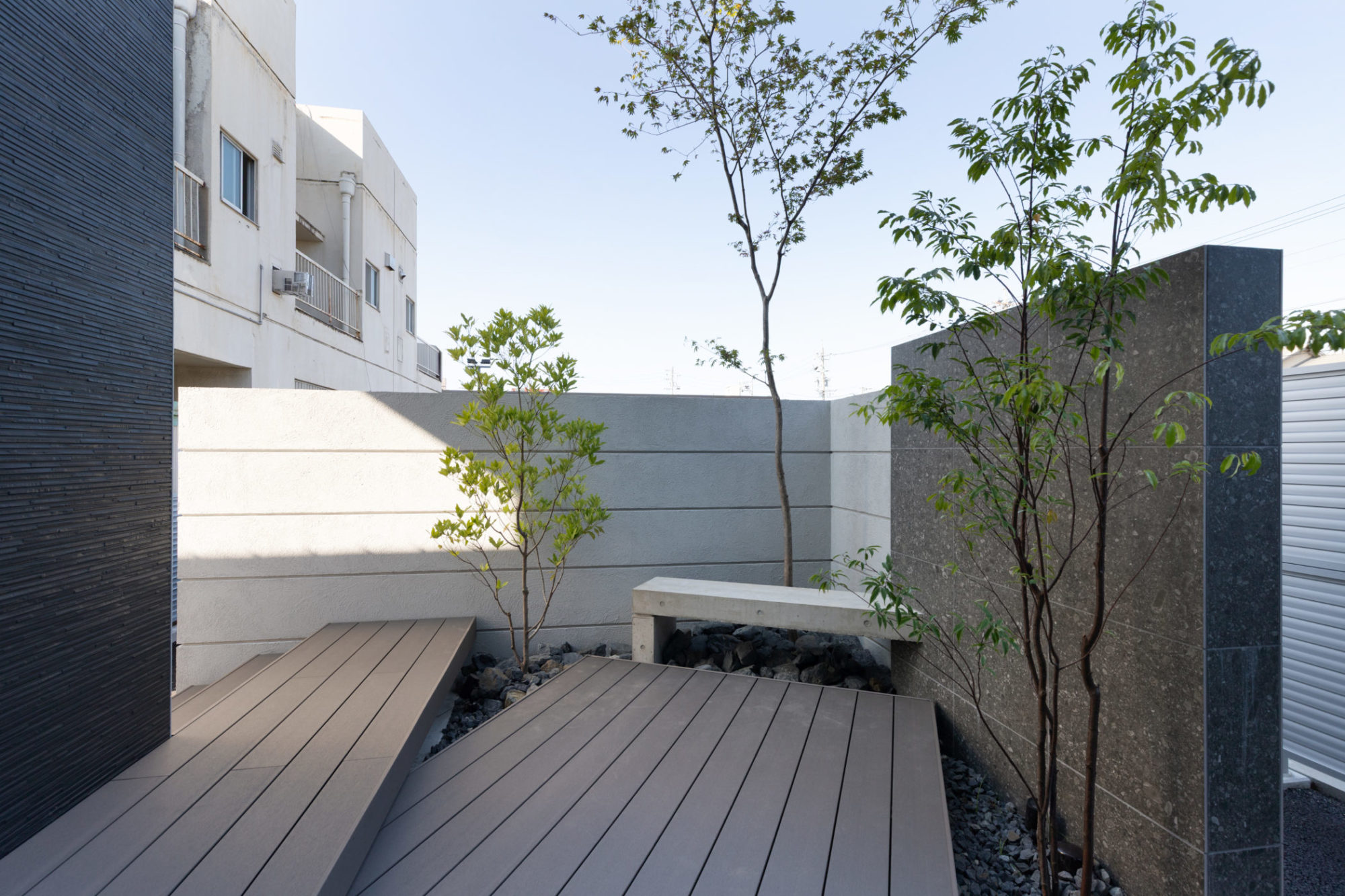 外壁で囲われたプライベートな中庭。ウッドデッキとベンチを配し、植栽が四季の変化を優しく感じさせます。