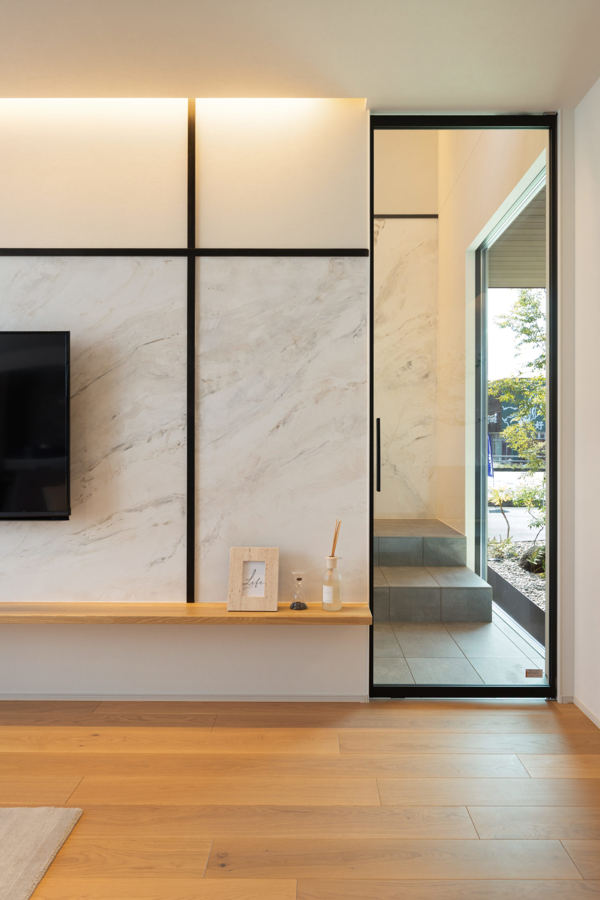 テレビ背面と玄関ホールに施した大理石調塗装のアクセントウォールの写真