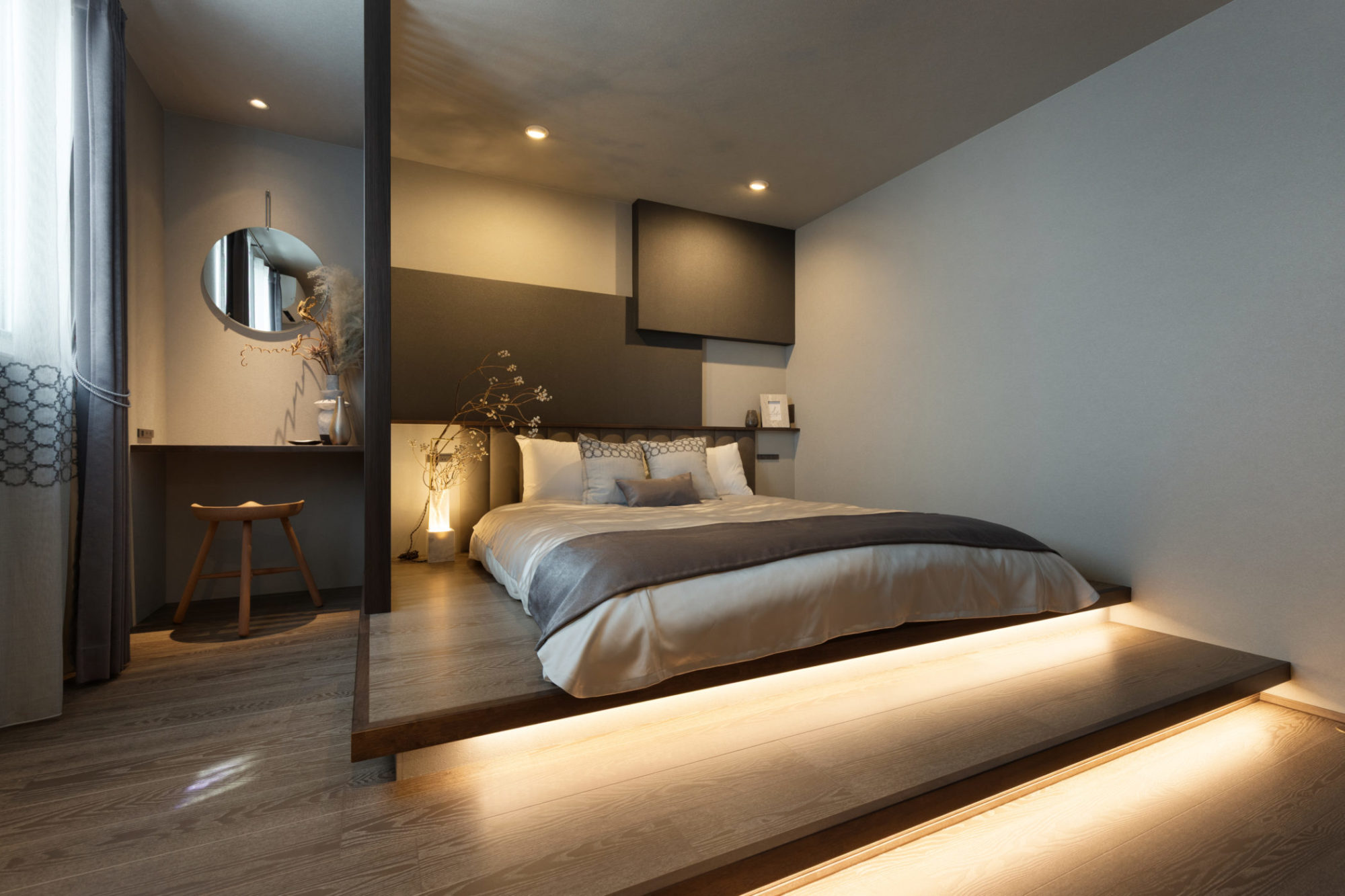 寝室の写真｜ダークフローリング、床上げ設計の寝室、2段ステップに間接照明