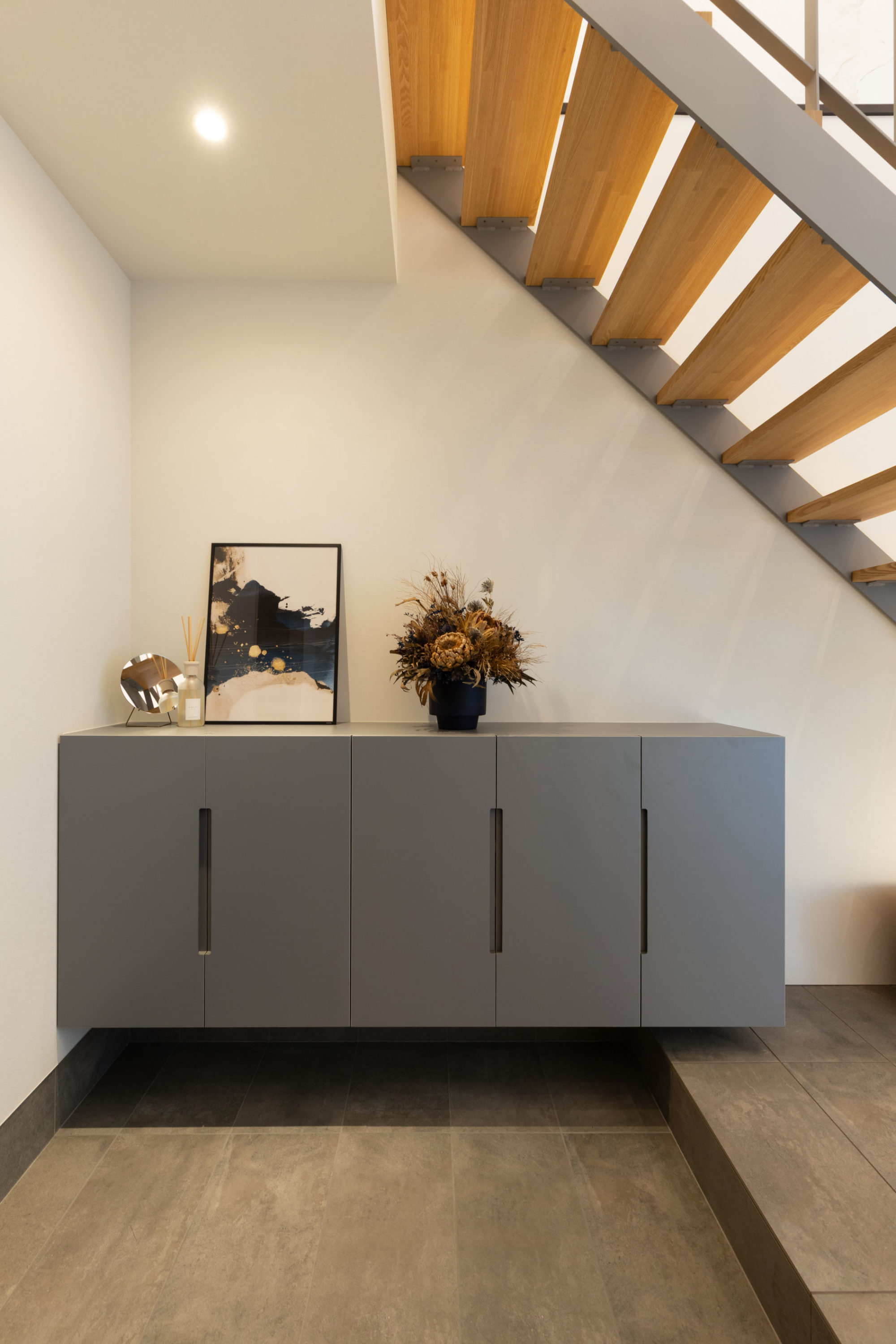 玄関ホールの写真｜造作玄関収納、鉄骨階段の色味と調和したグレーデザイン