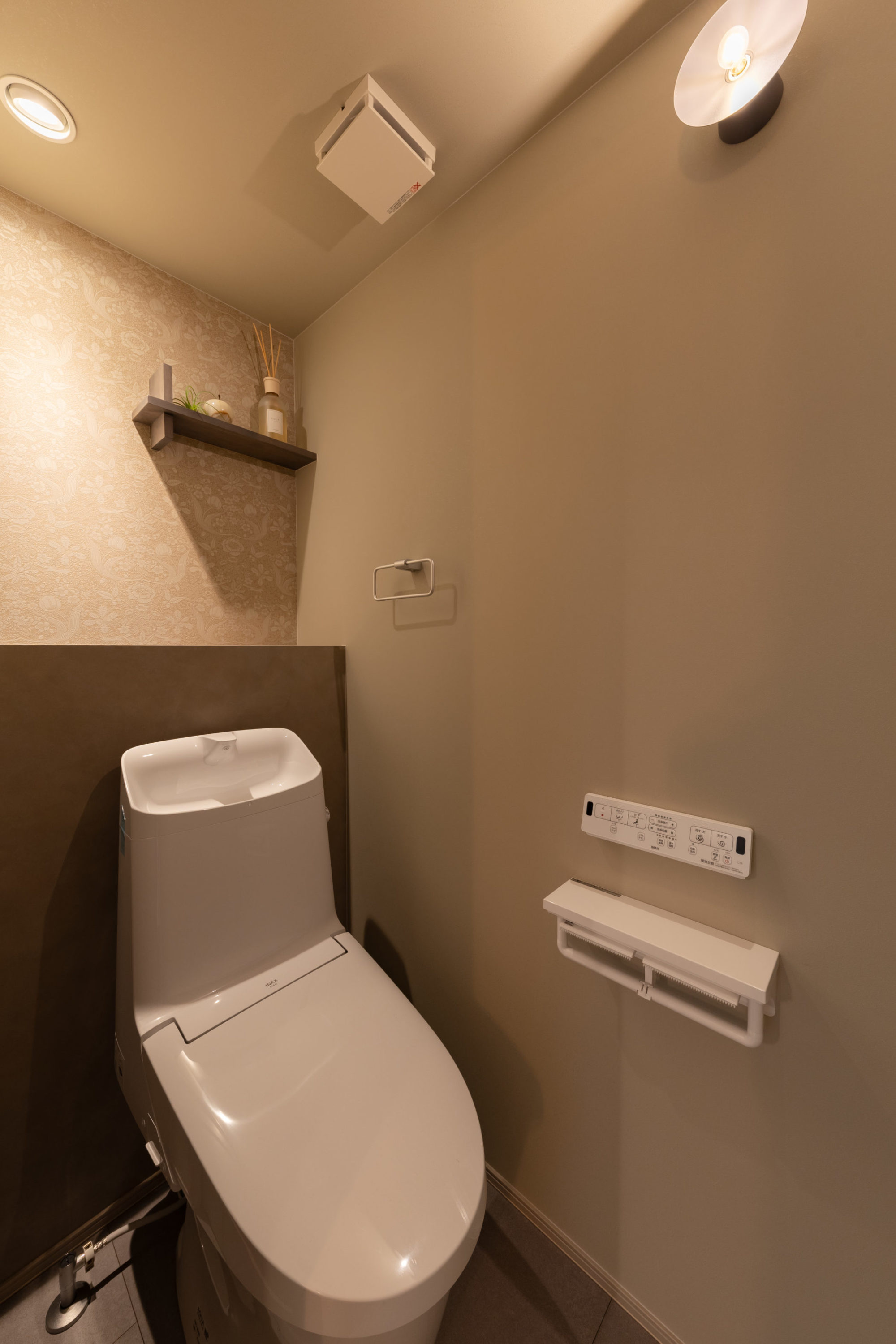 グレージュ色のクロスをベースに、動物や植物を描いたクラシカル柄のアクセントクロスを施したトイレ。