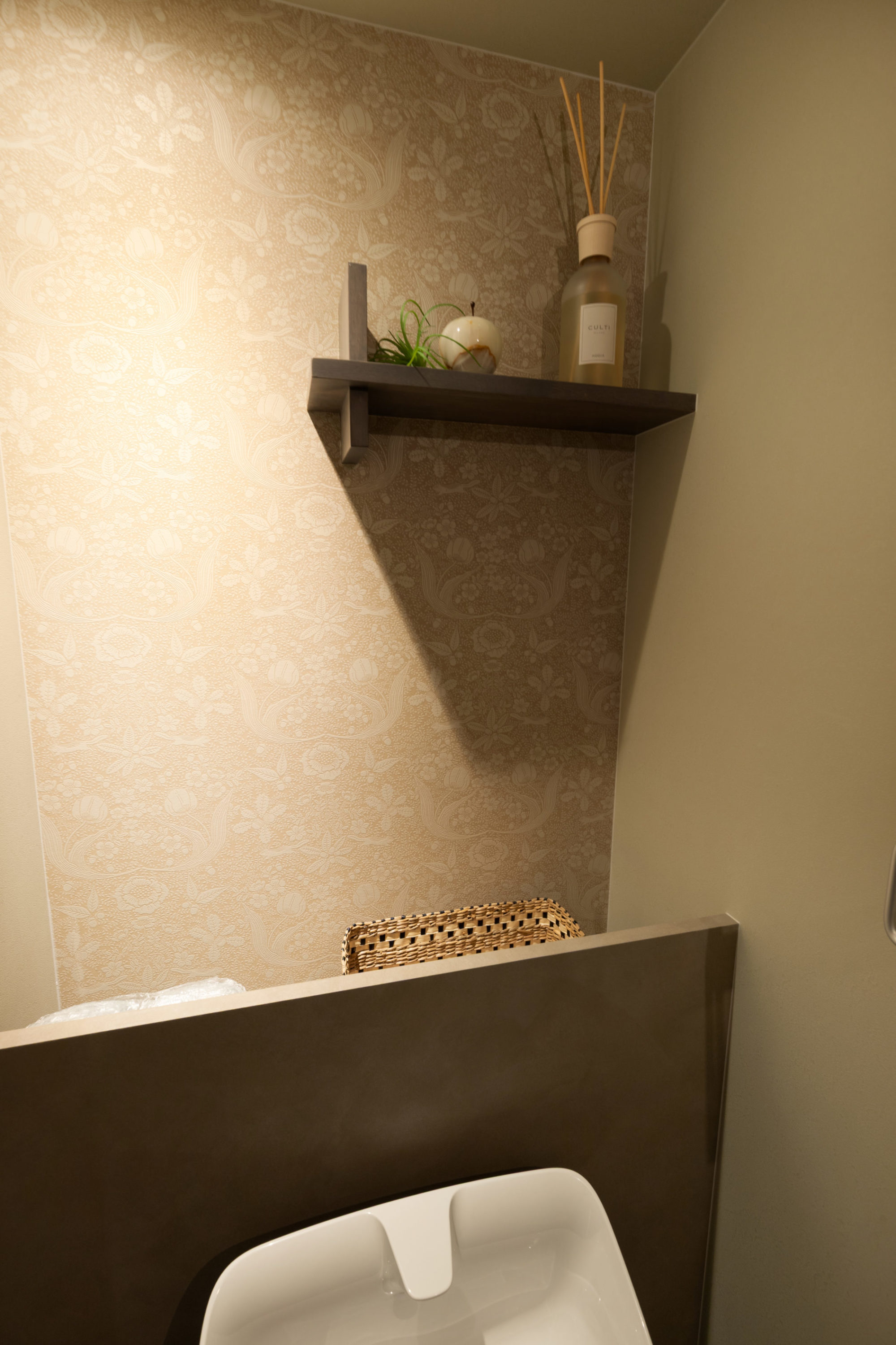 トイレの背面に設置した見えない収納。上から出し入れする仕様。