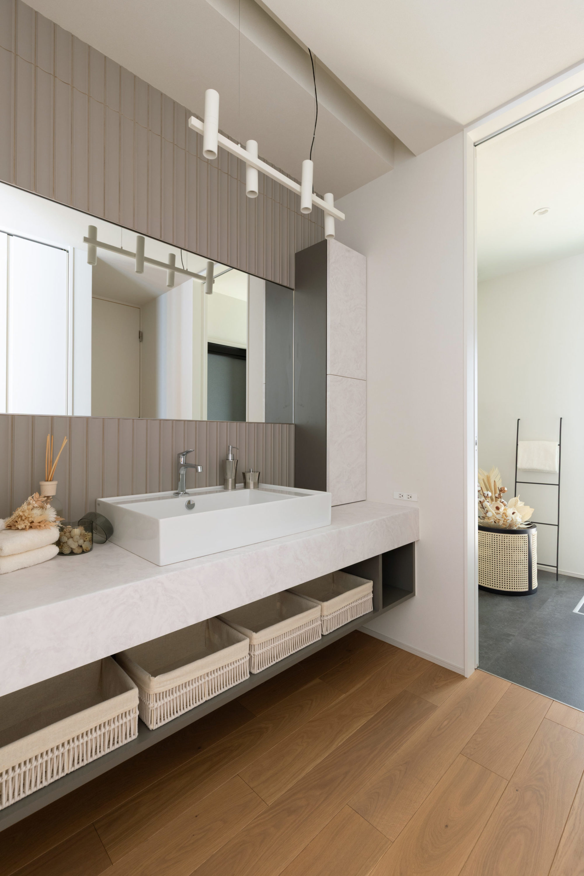 洗面台の写真｜直線的カウンターと曲線タイル、見せる収納と扉付き隠す収納を設置