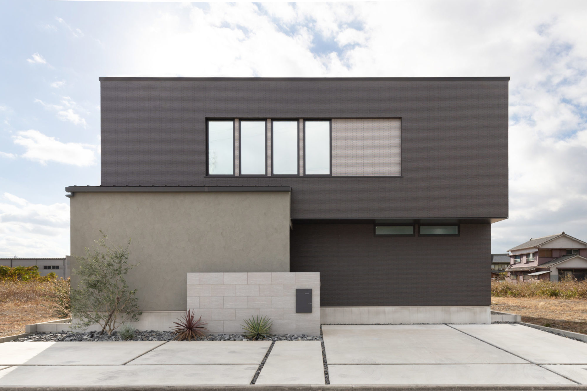 BOXを組み合わせたシンプルな外観。タイルをベースに、グレーの塗り壁がアクセント。