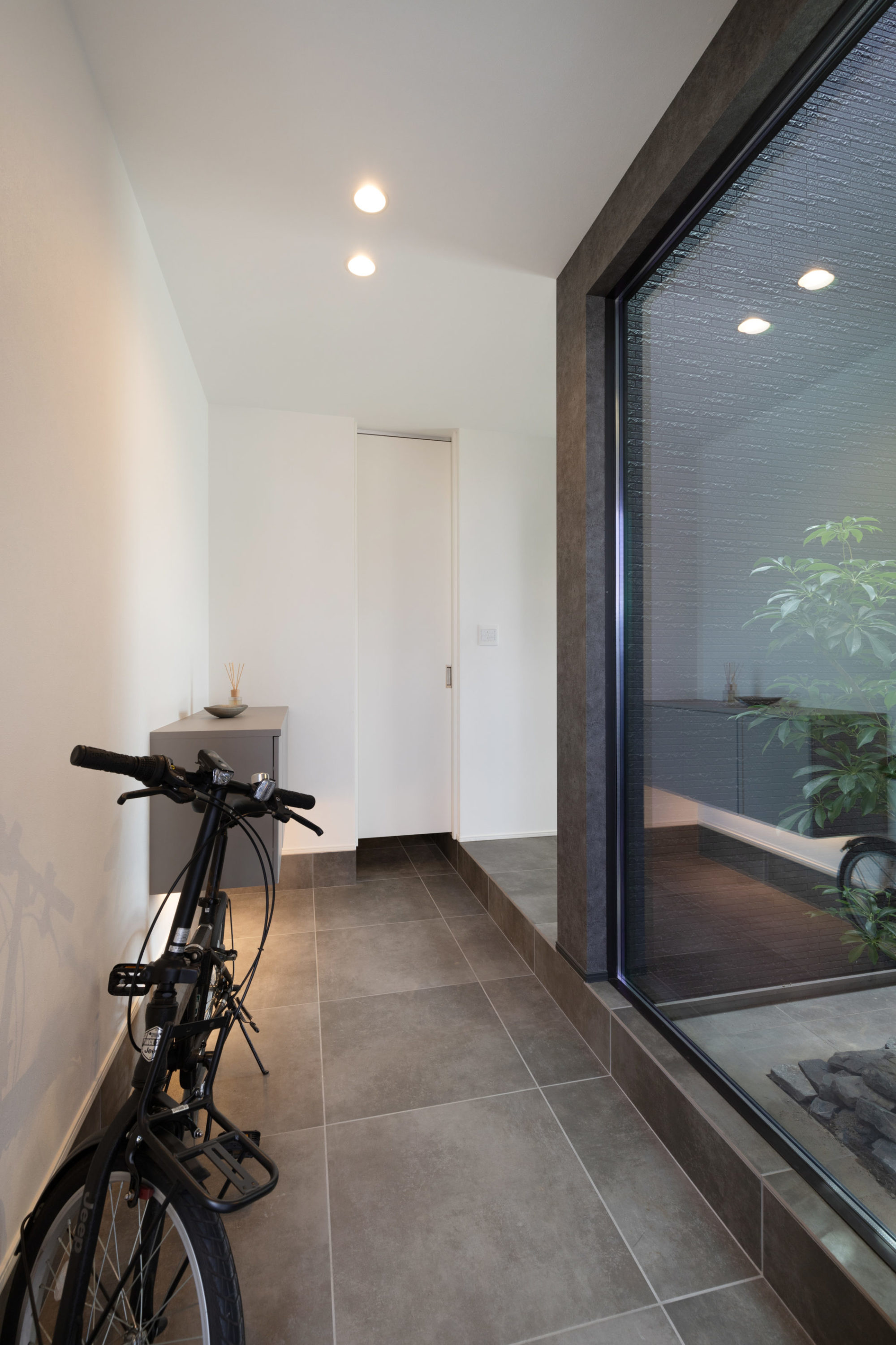 坪庭の緑と自然光が優しく迎える玄関。