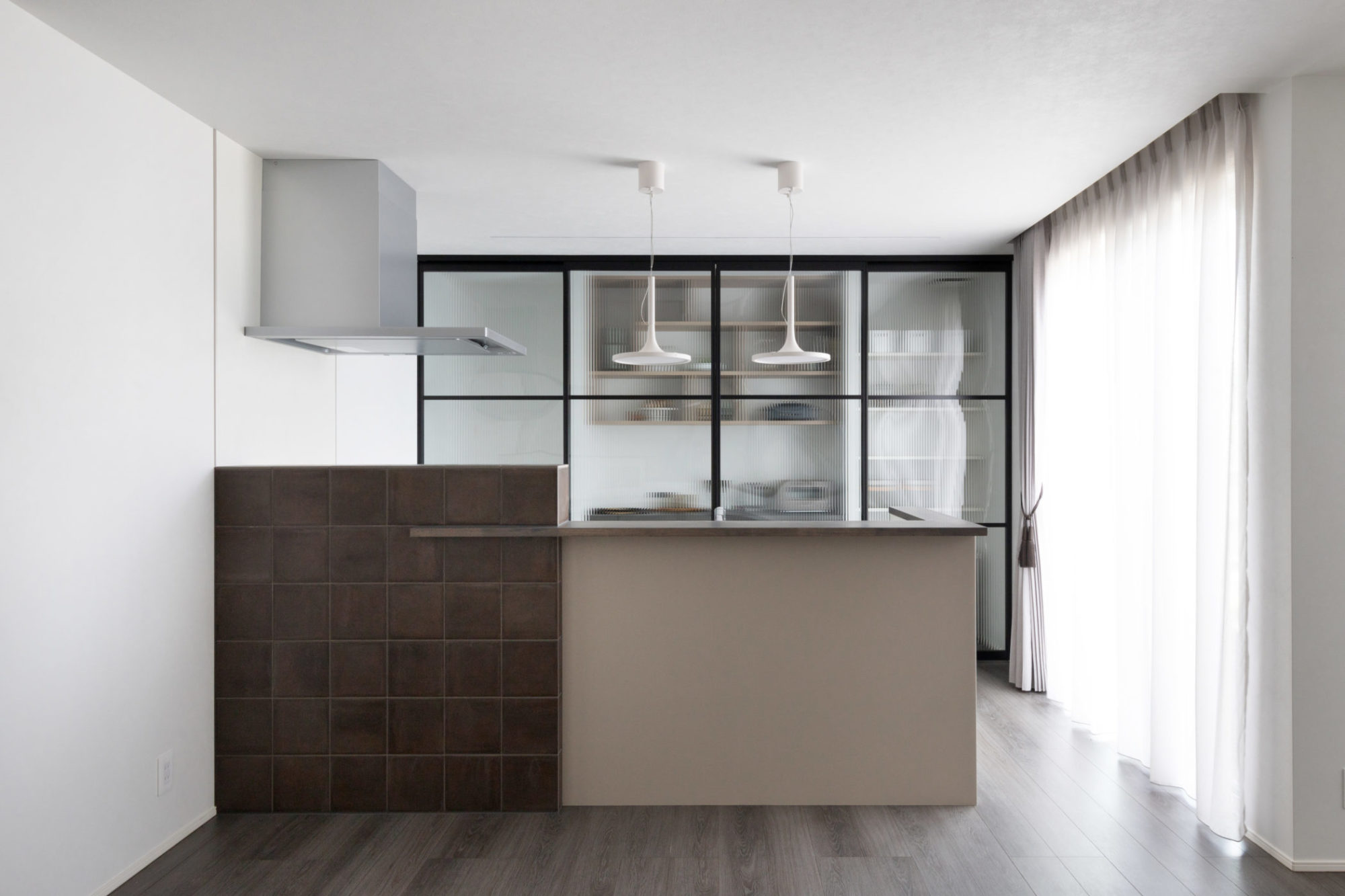 手元の目隠しとしても機能するキッチン腰壁。腰壁の一部にはテラコッタ風のブラウンタイルを貼って空間を引き締めました。