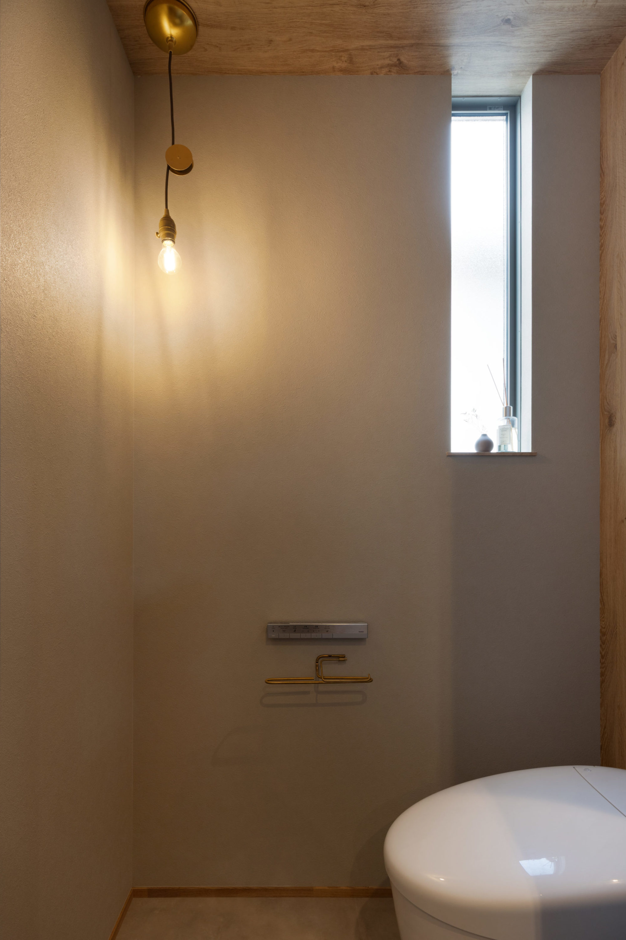 グレージュと木目でまとめた落ち着きのあるトイレ。