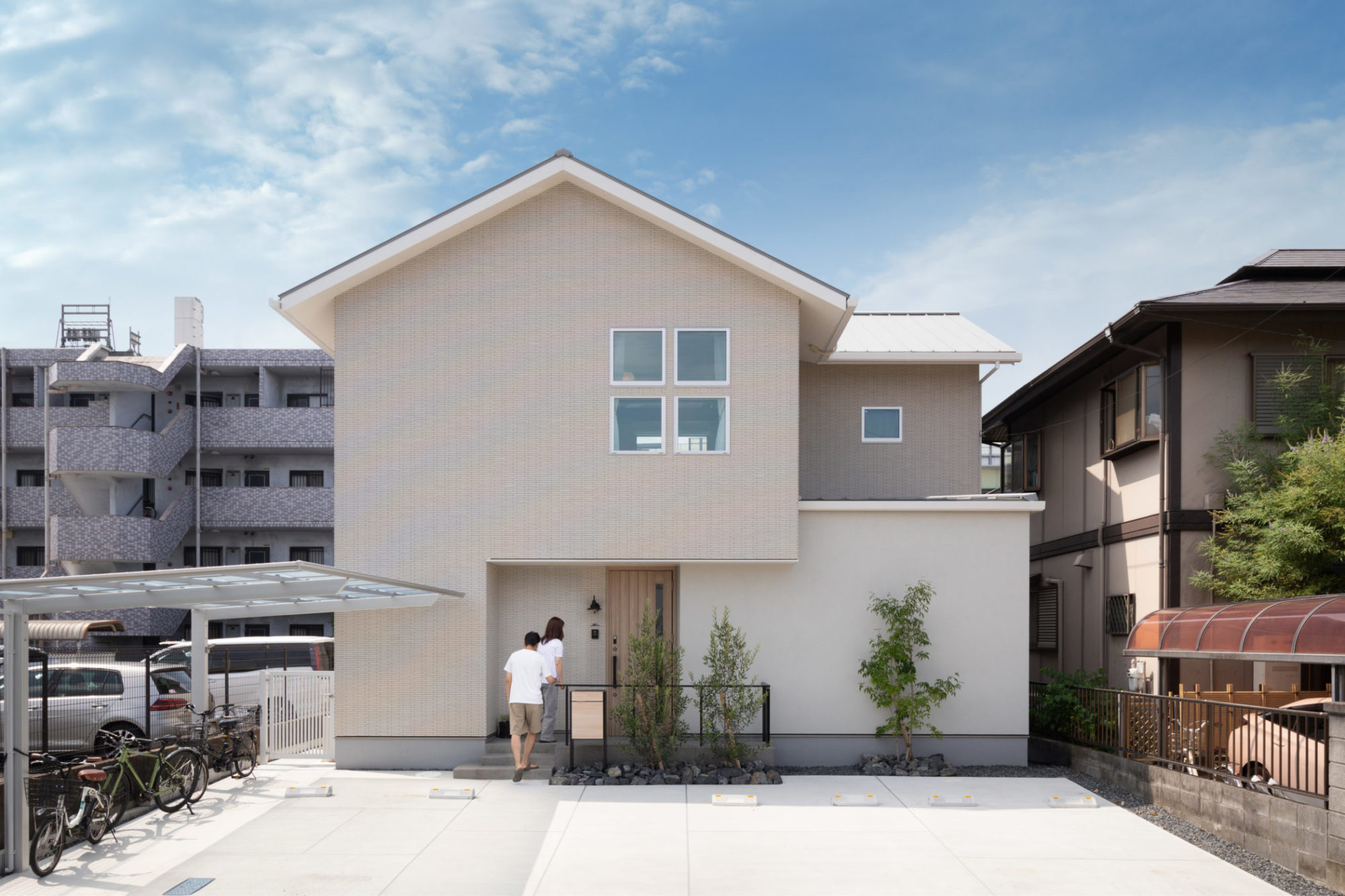 寄り添うように佇む切妻屋根の外観。柔らかな色合いのタイルと塗り壁を取り入れたナチュラルなデザイン。