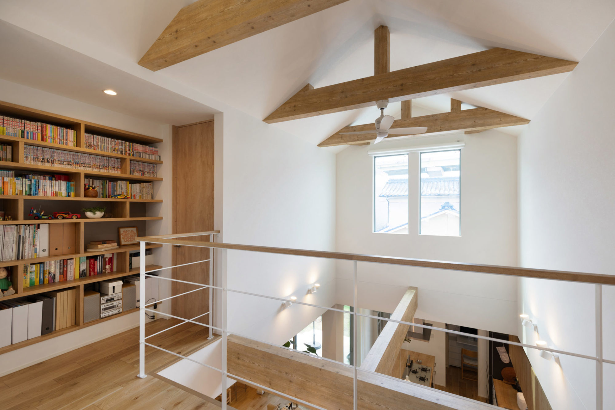 三角の勾配天井と表し梁が印象的な吹き抜けと、2階ホールに設けた造作本棚